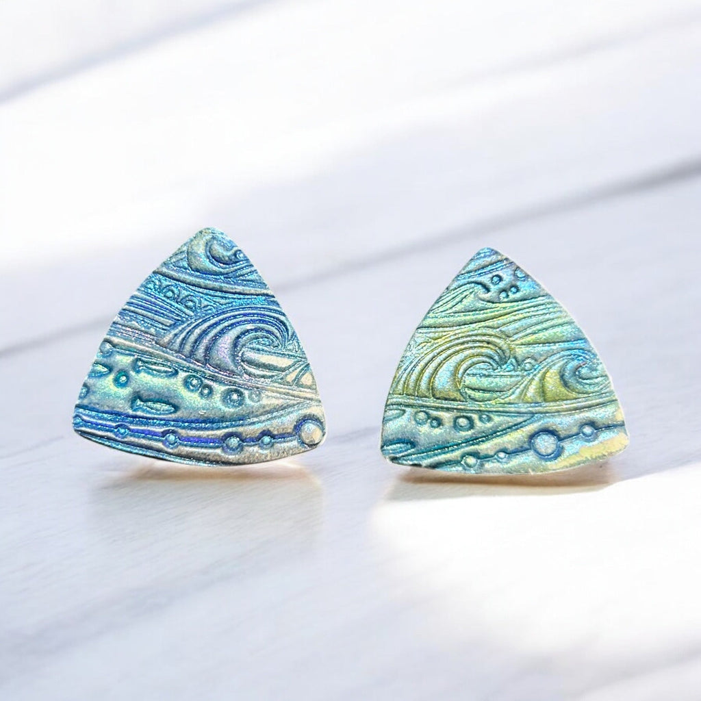 Triangular earrings with a textured, iridescent ocean wave design on a white background