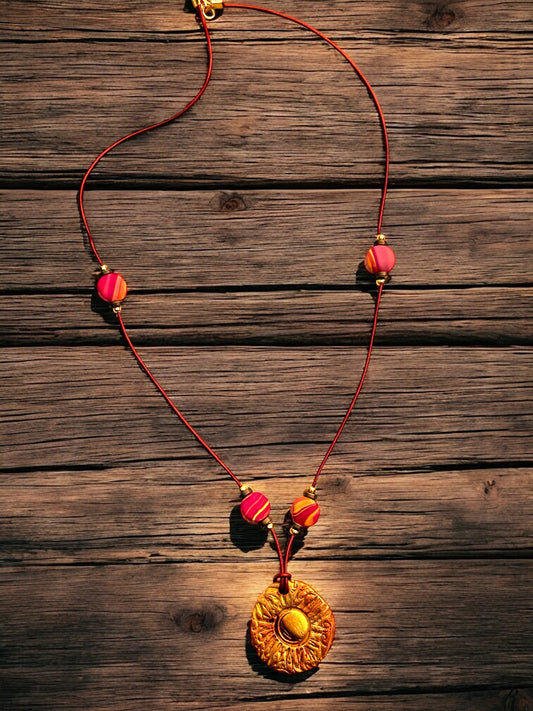 Sunburst Necklace with red cord and colorful beads on a wooden surface