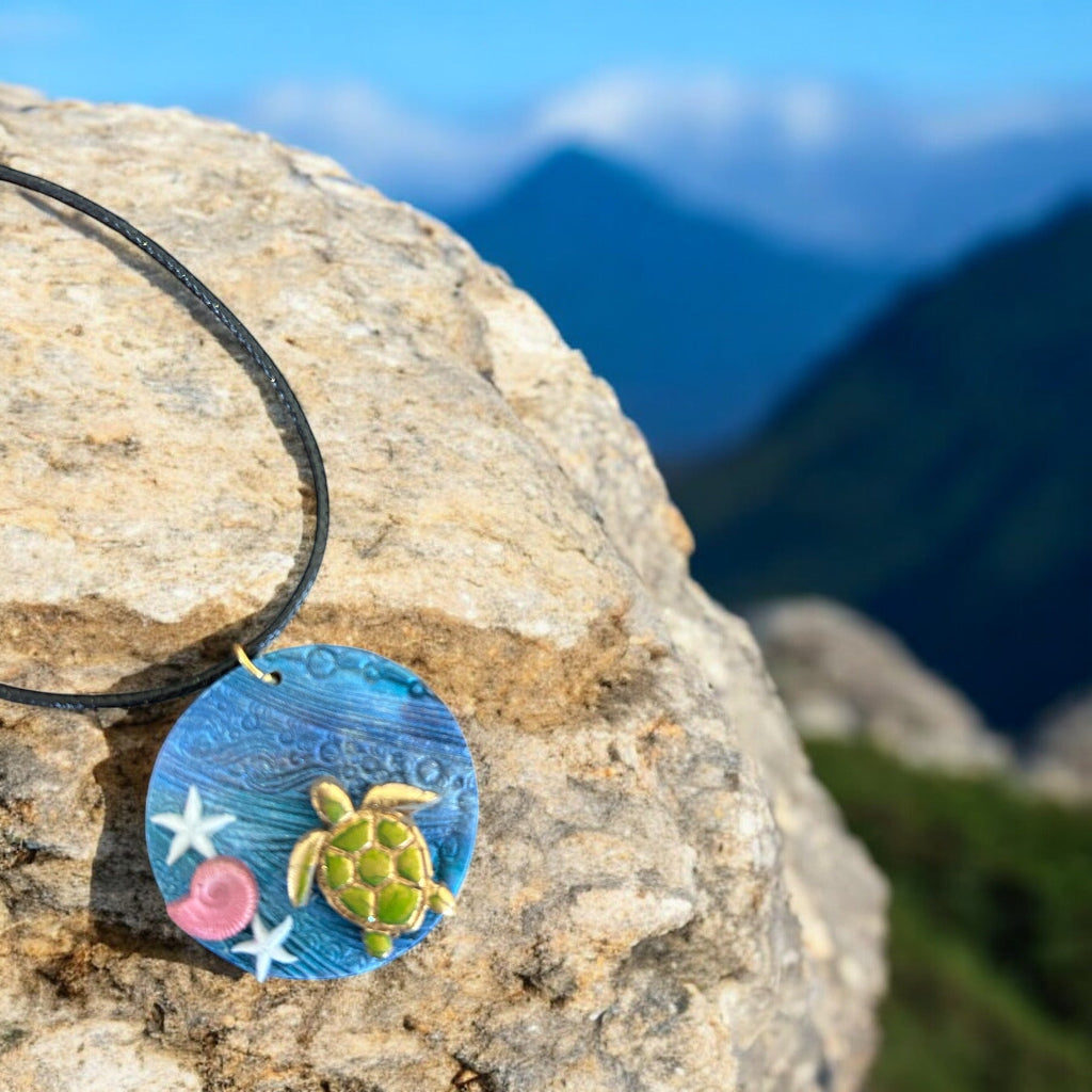 Necklace with a turtle pendant on a rock with mountains in the background