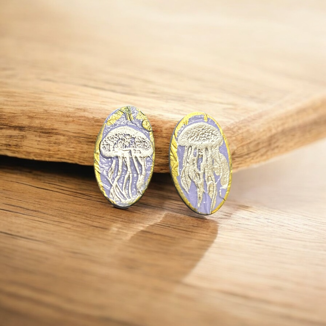 Pair of earrings with a jellyfish design on a wooden surface