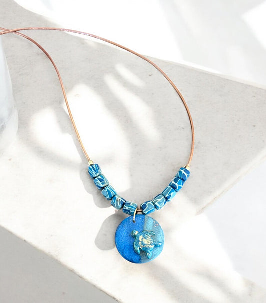 Necklace with blue beads and pendant on a light background