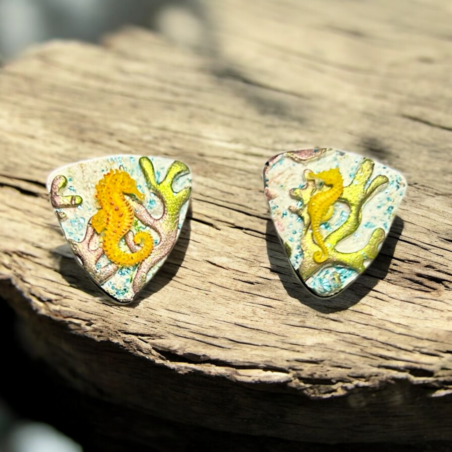 Pair of earrings with seahorse design on a wooden surface