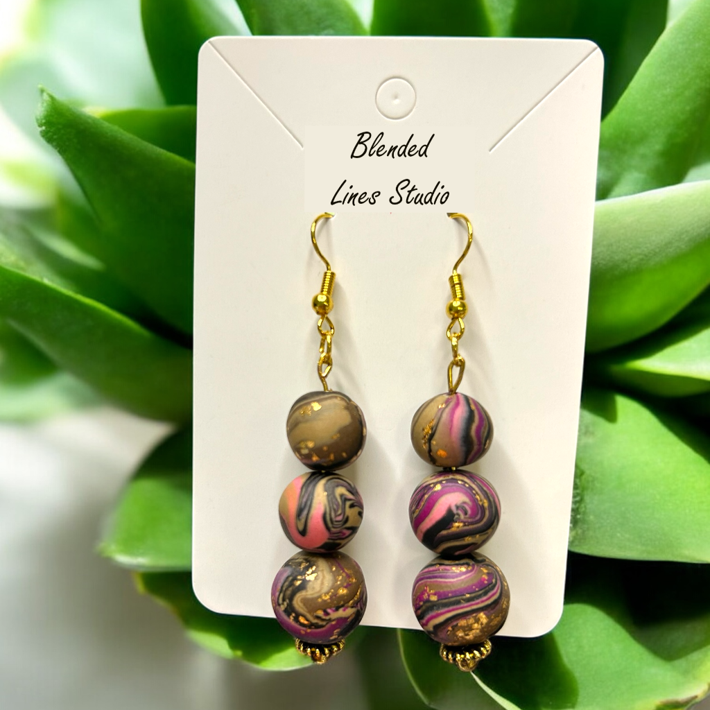 Marbled bead earrings on a Blended Lines Studio card with green leaves in the background