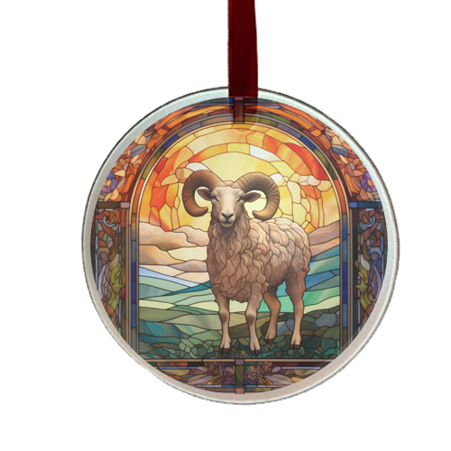 A round glass ornament featuring a stained glass window design with a ram in the center, surrounded by a colorful landscape and a red satin ribbon at the top.